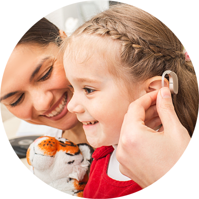 A hearing aid being placed in a smiling child's ear